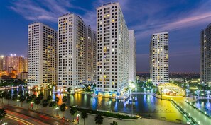 A high-rise residential building complex with multiple floors, a central courtyard with a fountain, and surrounding greenery. - SOL- Vinhomes Times City & Park Hill (Hanoi)