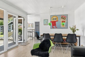 A modern dining area with a wooden table, black chairs, and a green chair with a black furry seat. - Lovely house with sea view and large terrace (Karrebæksminde)