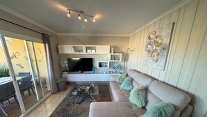 A modern living room with a beige sofa, a glass coffee table, and a flat-screen TV on a white entertainment unit. - CLEMENVILLA III (Denia)