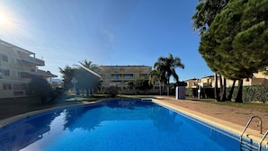 A clear swimming pool with a sunlit sky, surrounded by buildings and trees. - CLEMENVILLA III (Denia)