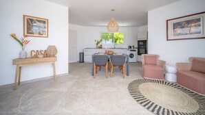 Una sala moderna con comedor, cocina y un amplio ventanal que proporciona luz natural.