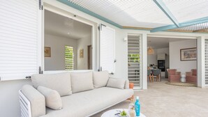 Una sala de estar moderna con un sofá, una mesa redonda con bebidas y vistas a la cocina y el comedor.