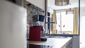 Una cucina moderna con piano cottura integrato, macchina del caffè e porta pentole a sospensione.