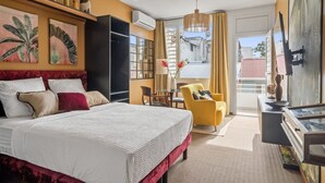 Camera d'albergo con un letto grande, una scrivania, una sedia, una televisione e un balcone con vista.