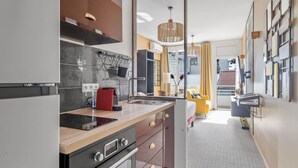 Una cucina moderna con piano cottura integrato, lavello ed un bollitore rosso. C'è un bancone in legno e un lampadario.