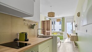 Moderni keittiö, jossa on sisäänrakennettu liesi, pesuallas ja vihreä työtaso. Keittiössä on ruokailutila, jossa on pöytä ja tuolit, sekä ikkuna, jossa on verhot.