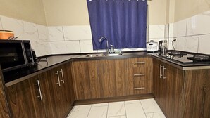 A kitchen with wooden cabinets, a sink, a stove, and a microwave.