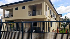 A multi-story residential building with a gated entrance, balconies, and a clear sky.