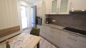 Een moderne keuken met een koelkast, oven, koffiezetapparaat en een eethoek met tafel en stoel.