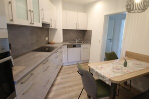Een moderne keuken met witte kasten, een spoelbak en een eethoek met een tafel en stoelen.