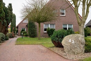 Une maison en briques avec le numéro 43, un chemin pavé et un jardin bien entretenu.