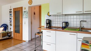 A kitchen with white cabinets, a sink, a coffee maker, and a kettle.