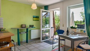 A kitchen with a table and chairs, a radiator, a window with curtains, and a door leading outside.