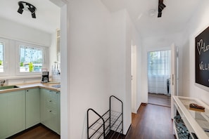 A kitchen with a coffee maker, a metal rack, and a chalkboard with writing.