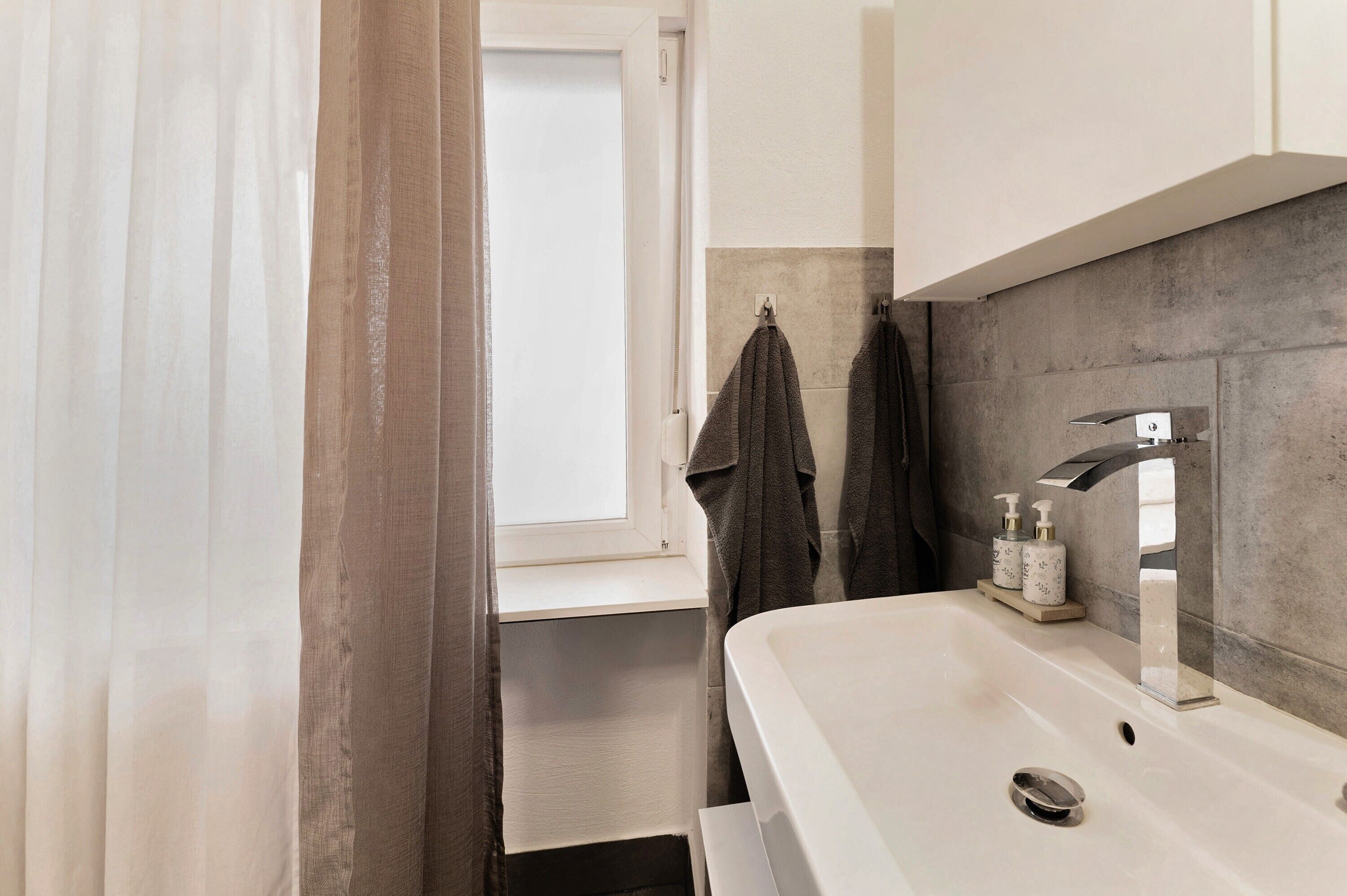 Une salle de bain avec un lavabo blanc, un miroir, un porte-serviettes et un rideau de douche.