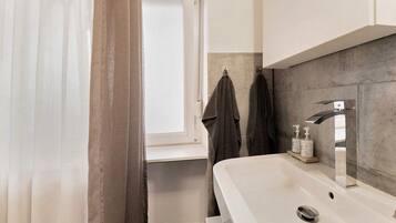 Une salle de bain avec un lavabo blanc, un miroir, un porte-serviettes et un rideau de douche.