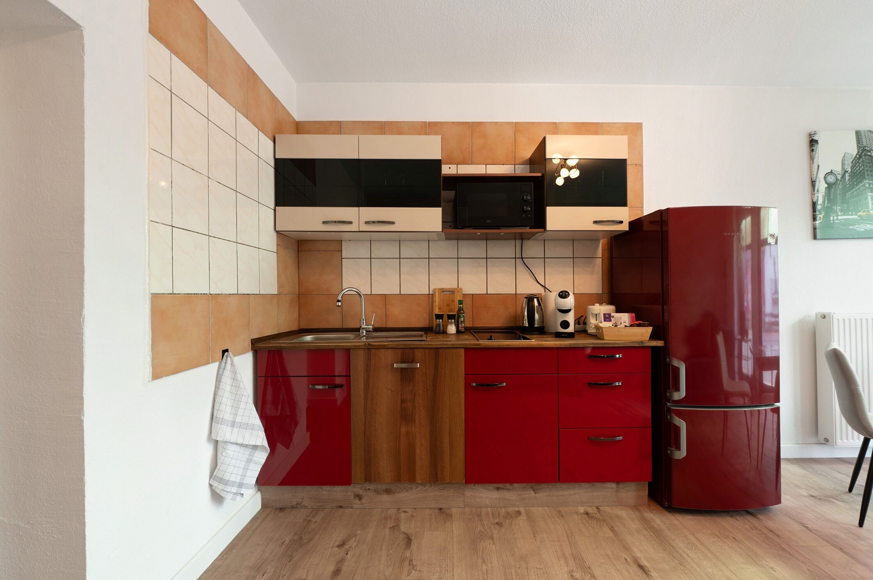 Una cocina funcional con microondas, estufa y refrigerador rojo.