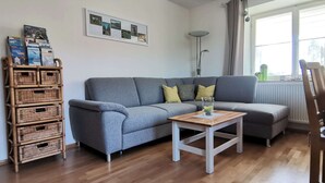 A living room with a grey sofa, a wooden coffee table, wicker storage, a framed picture, and a floor lamp.