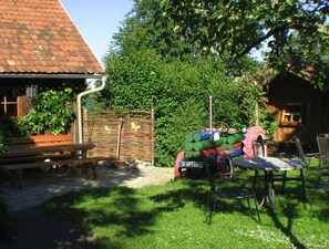 A rustic outdoor area with a wooden bench, a metal chair, and a table. - Holiday Apartment 'Jägerstube' with Shared Terrace, Shared Garden and Wi-Fi (Wilhelmsdorf)
