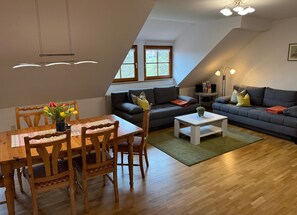 Un espacio habitable tipo loft con comedor, sofá, mesa de centro y mueble para televisión.