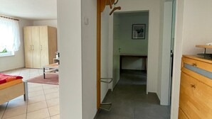 Un pasillo con una cama, un aparador de madera y una zona de cocina.