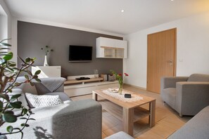 A modern living room with a sofa, a coffee table, a TV, and a cabinet.