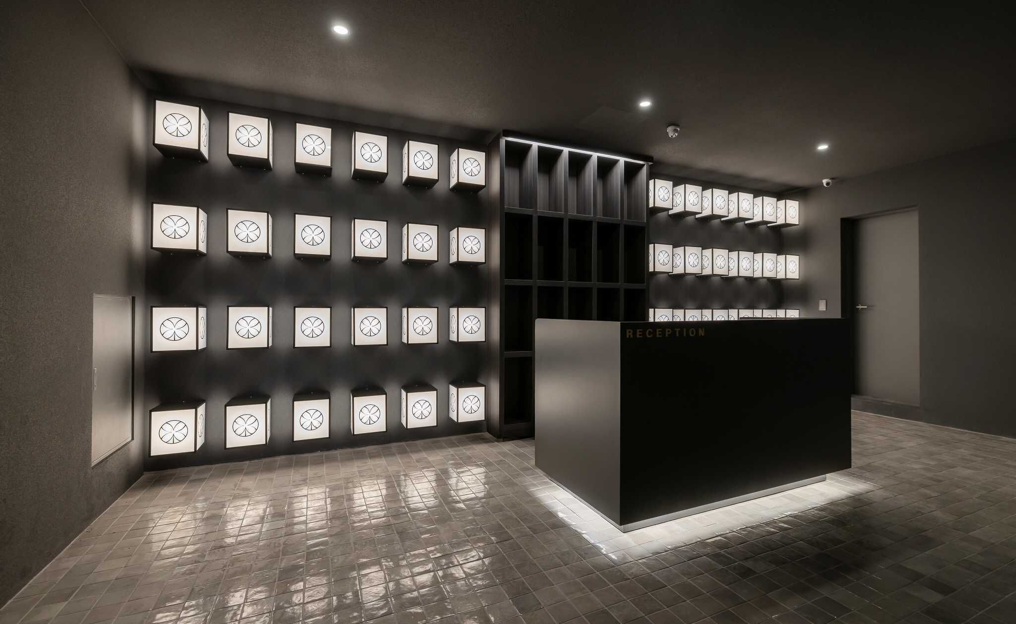 A reception area with a dark reception desk and a wall of illuminated square panels.