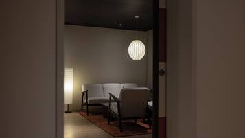 A modern living room with a sofa, armchairs, and a hanging light fixture.