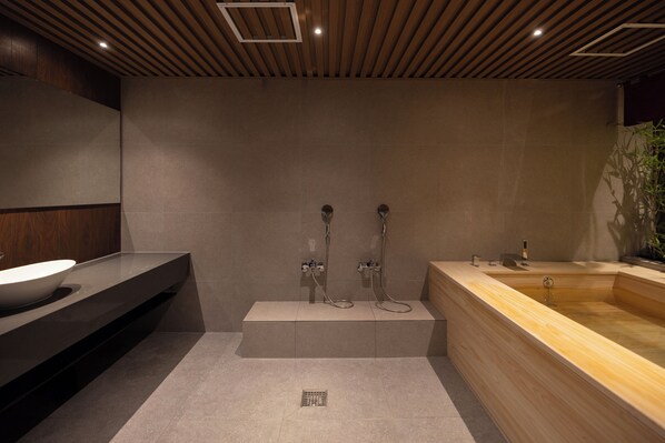 A modern bathroom with a wooden vanity, a freestanding bathtub, and a shower area.