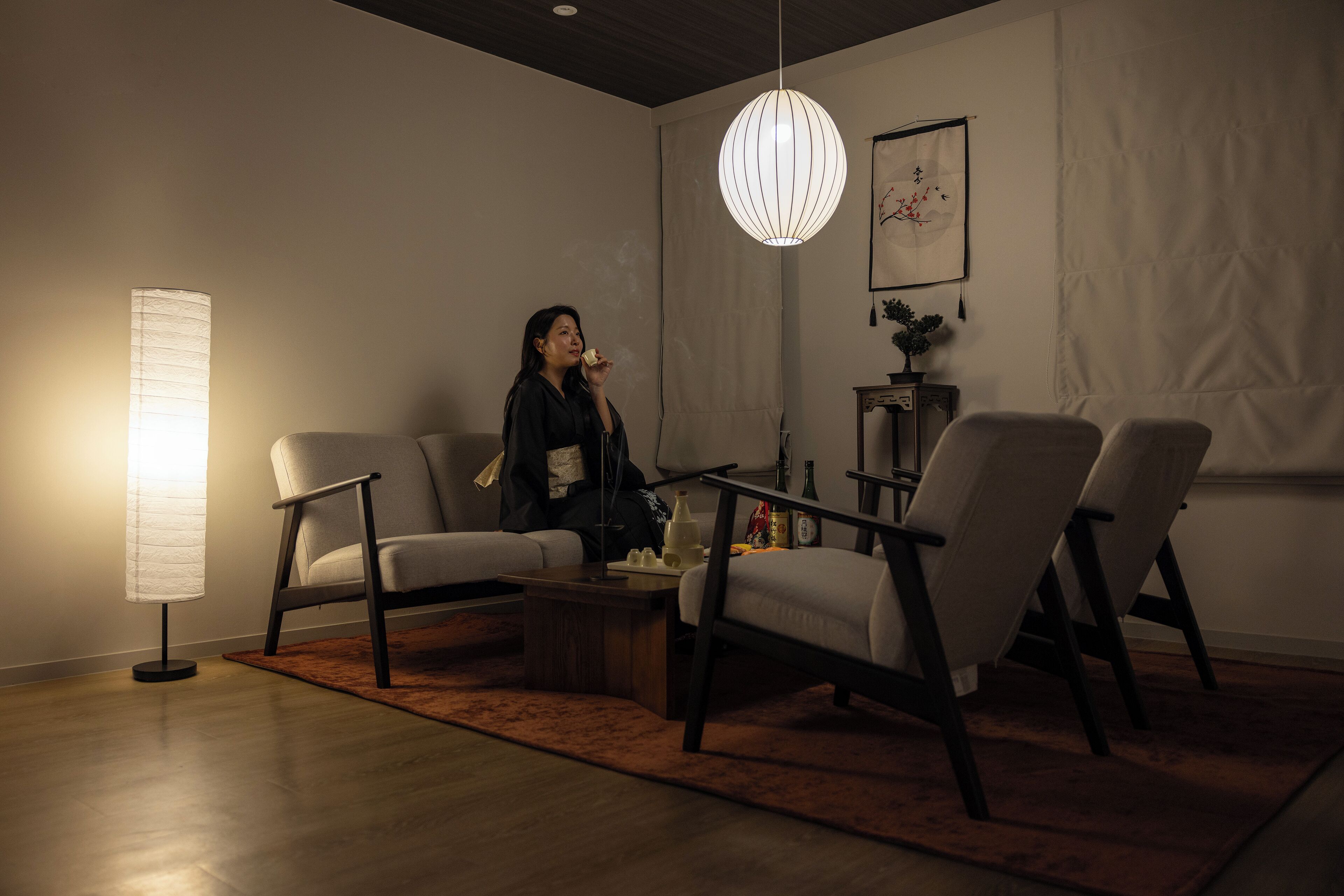 A modern living room with a sofa, two armchairs, a coffee table, and a hanging light fixture.