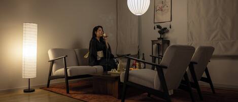 A modern living room with a sofa, two armchairs, a coffee table, and a hanging light fixture.