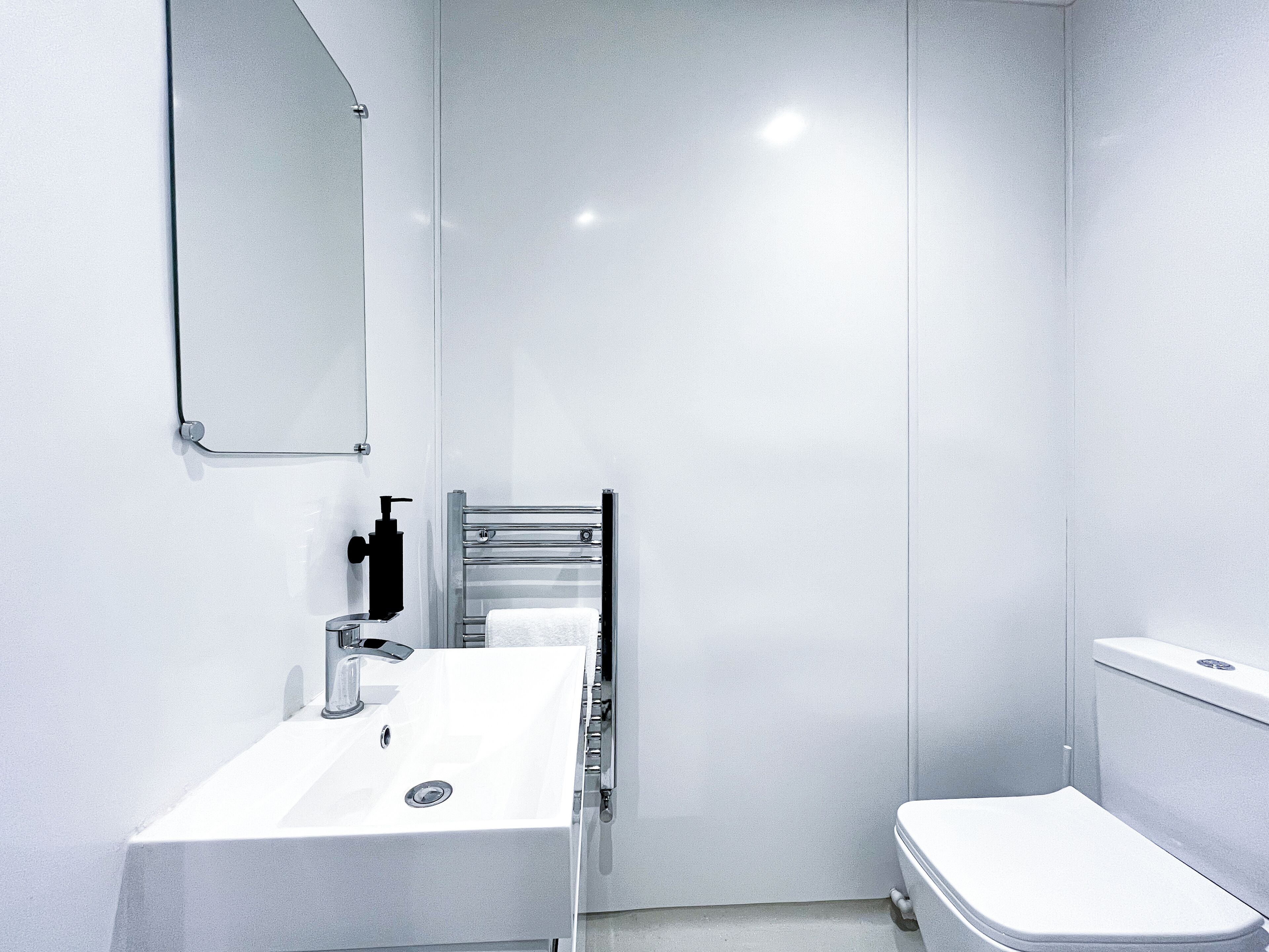 A modern bathroom with a white sink, a mirror, and a toilet.