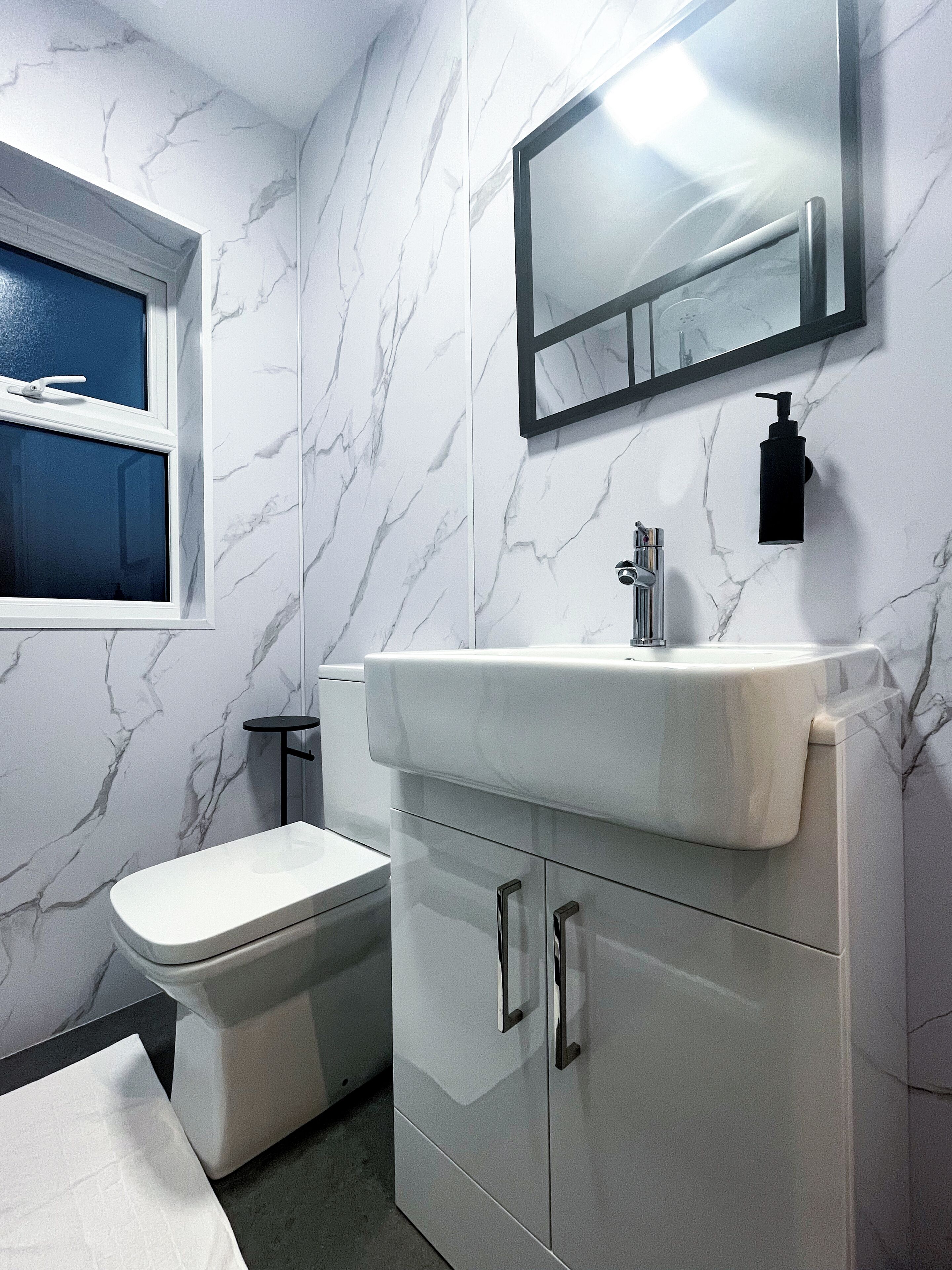 A bathroom with a toilet, sink, and mirror.