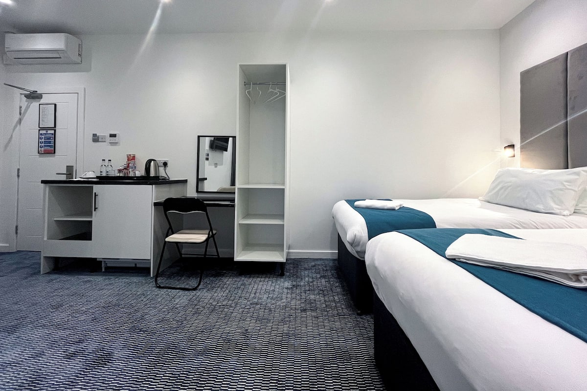 Una habitación de hotel con cama, escritorio, silla, armario y baño.