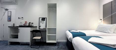 Een hotelkamer met een bed, een bureau, een stoel, een kast en een badkamer.