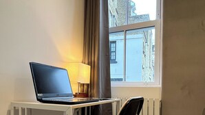 A small hotel room with a desk, chair, and a laptop. - Park Inn Palace (Dover)