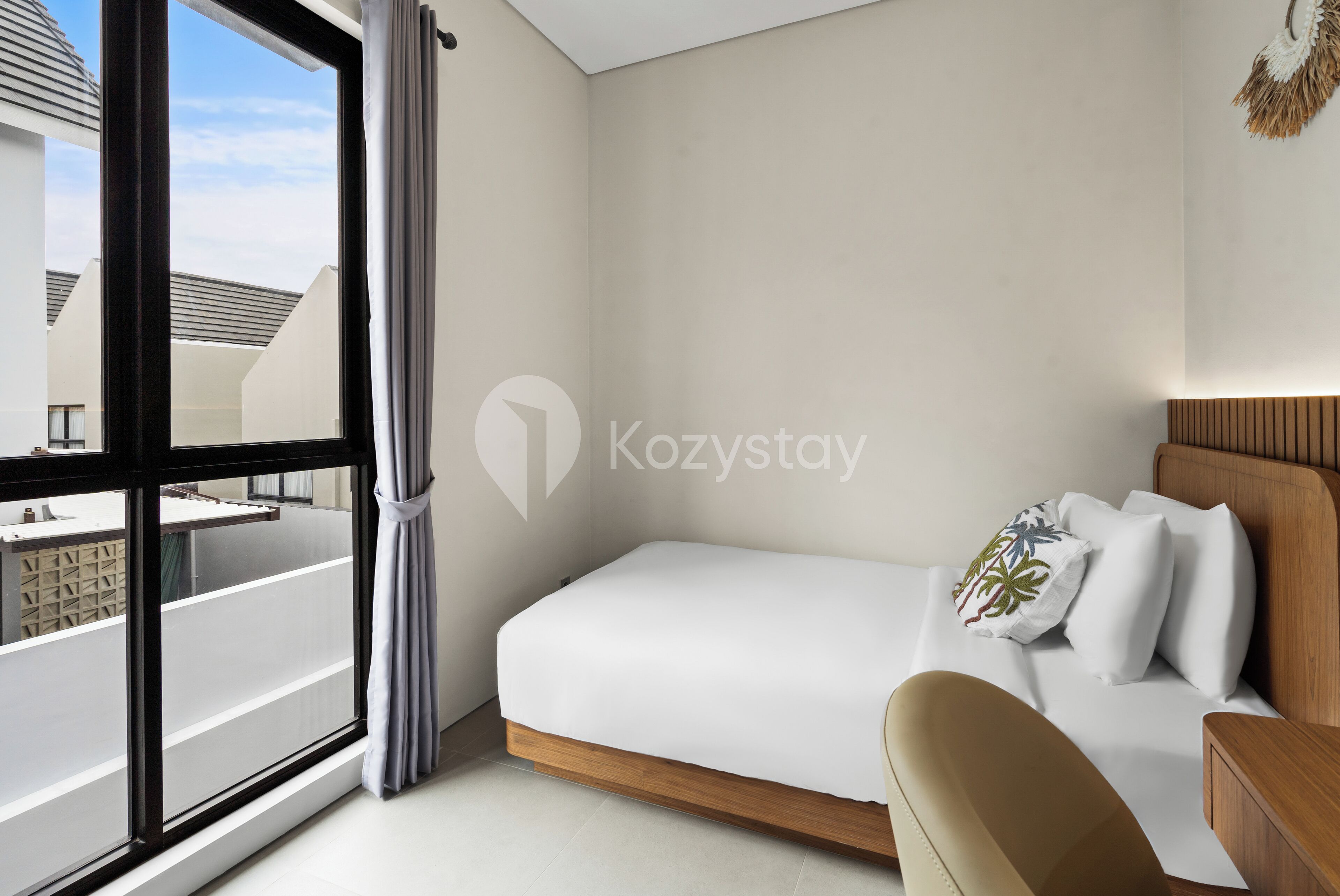 Una habitación de hotel moderna con un ventanal grande, una cama con ropa de cama blanca, un cabecero de madera y una mesita de noche pequeña.