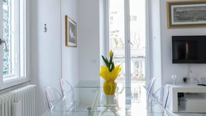 Una zona de menjador moderna amb taula i cadires de vidre, un llumeria i vistes per grans finestrals.