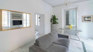 Un saló modern amb un sofà gris, una televisió de pantalla plana i una làmpada penjant.