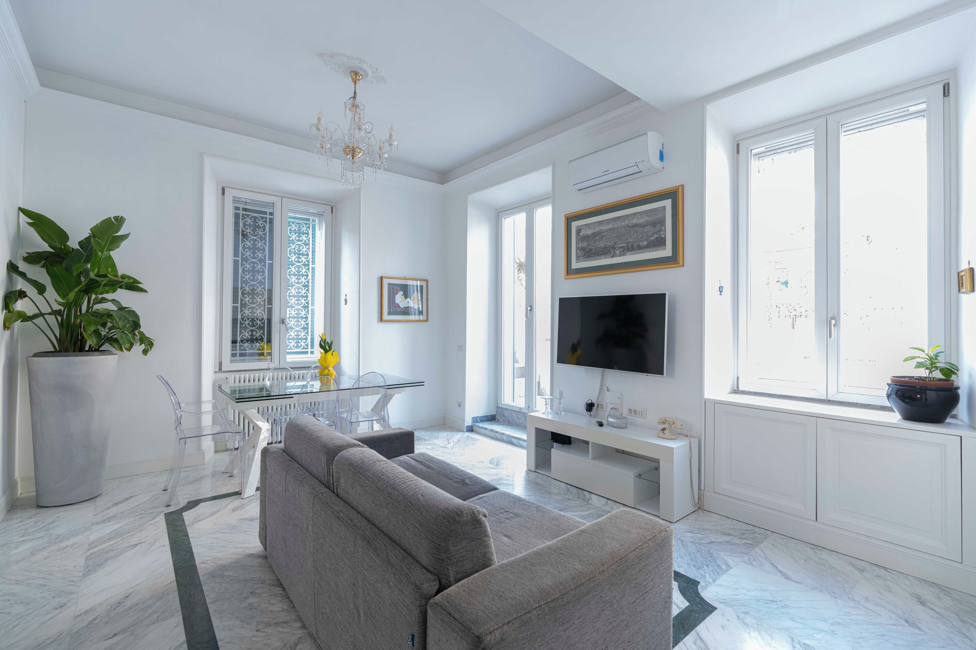 Una sala de estar moderna con un sofá gris, un televisor y un ventanal con vistas.