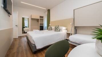 A modern hotel room with a bed, bedside table, chair, and a small table.