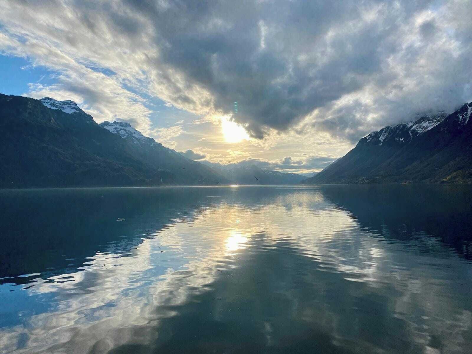Un lago tranquilo con montañas a ambos lados y un cielo nublado.