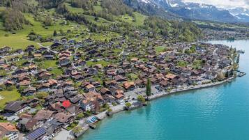 A lakeside village with traditional houses, a marina, and a backdrop of mountains.