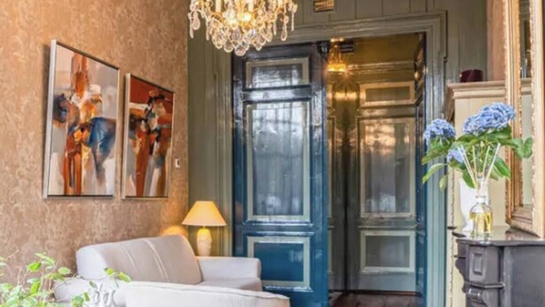 Una sala de estar acogedora con una araña, una puerta azul y una chimenea.