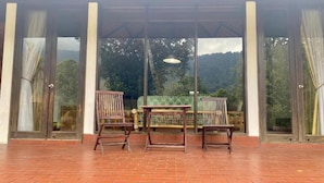 A covered patio area with a brick floor, a table, and two chairs.