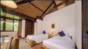 A room with two beds, a wooden bench, a glass table, and a large window.