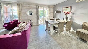 Una sala de estar con sofá, mesa de comedor y sillas, un espejo y un equipo de aire acondicionado.