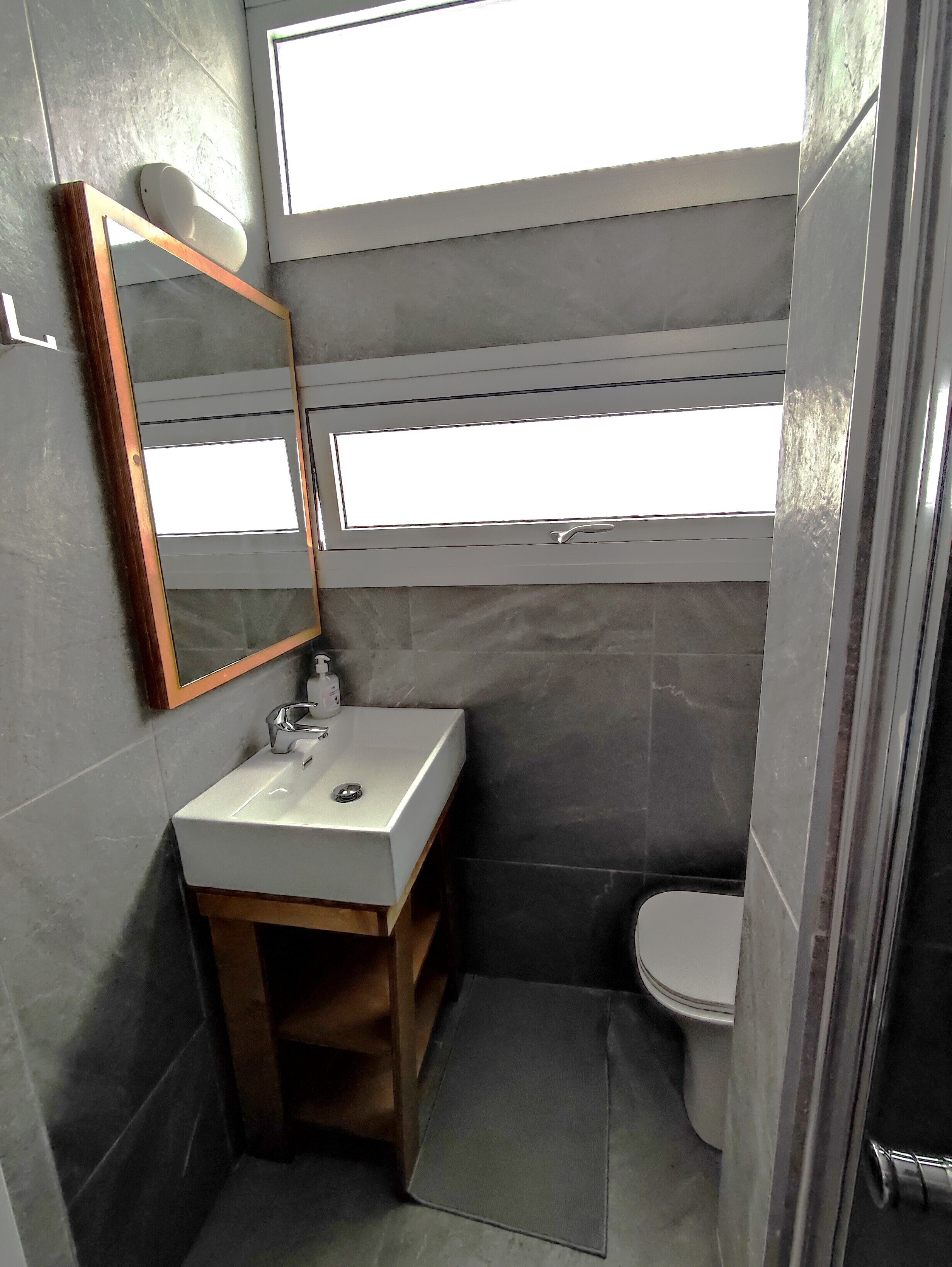 Un baño pequeño con un lavabo blanco, un espejo y un inodoro.