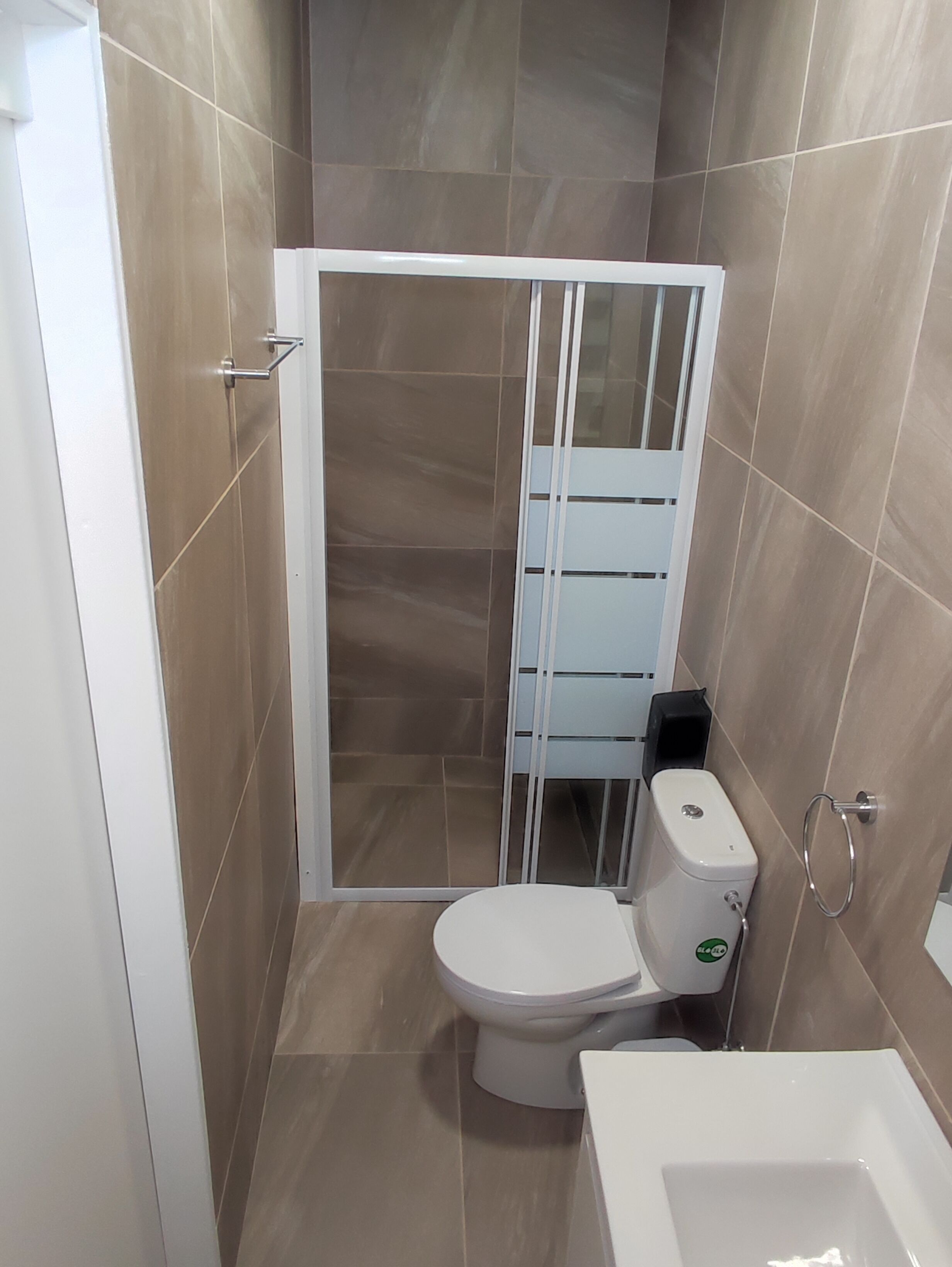 Un baño con inodoro, cabina de ducha y lavabo.