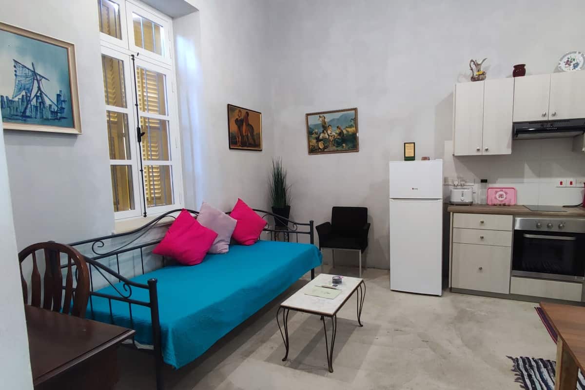 A compact living space with a bed, a small table, a kitchenette, and a dining area.